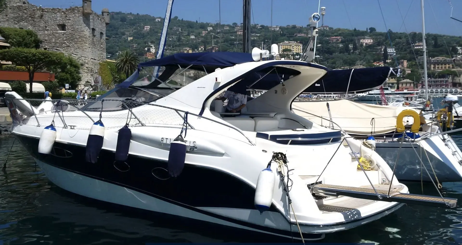 Atlantis 42 — Vedette blanche à moteur amarrée dans un port, vue de trois quarts arrière.