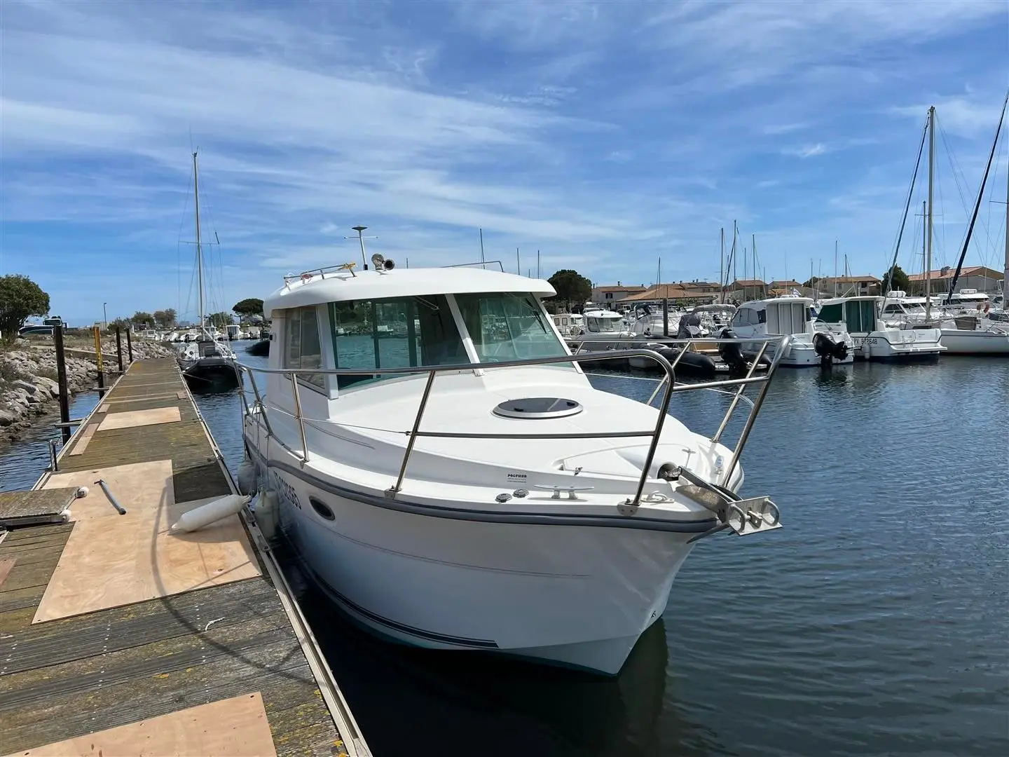 Ocqueteau 765 — Bateau à moteur blanc amarré dans un port de plaisance, vu de trois quarts avant.