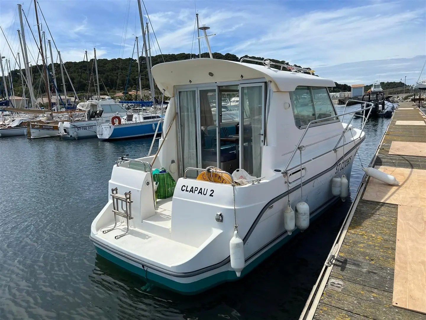 Ocqueteau 765 — Bateau à moteur blanc amarré dans un port, vu de trois quarts arrière.