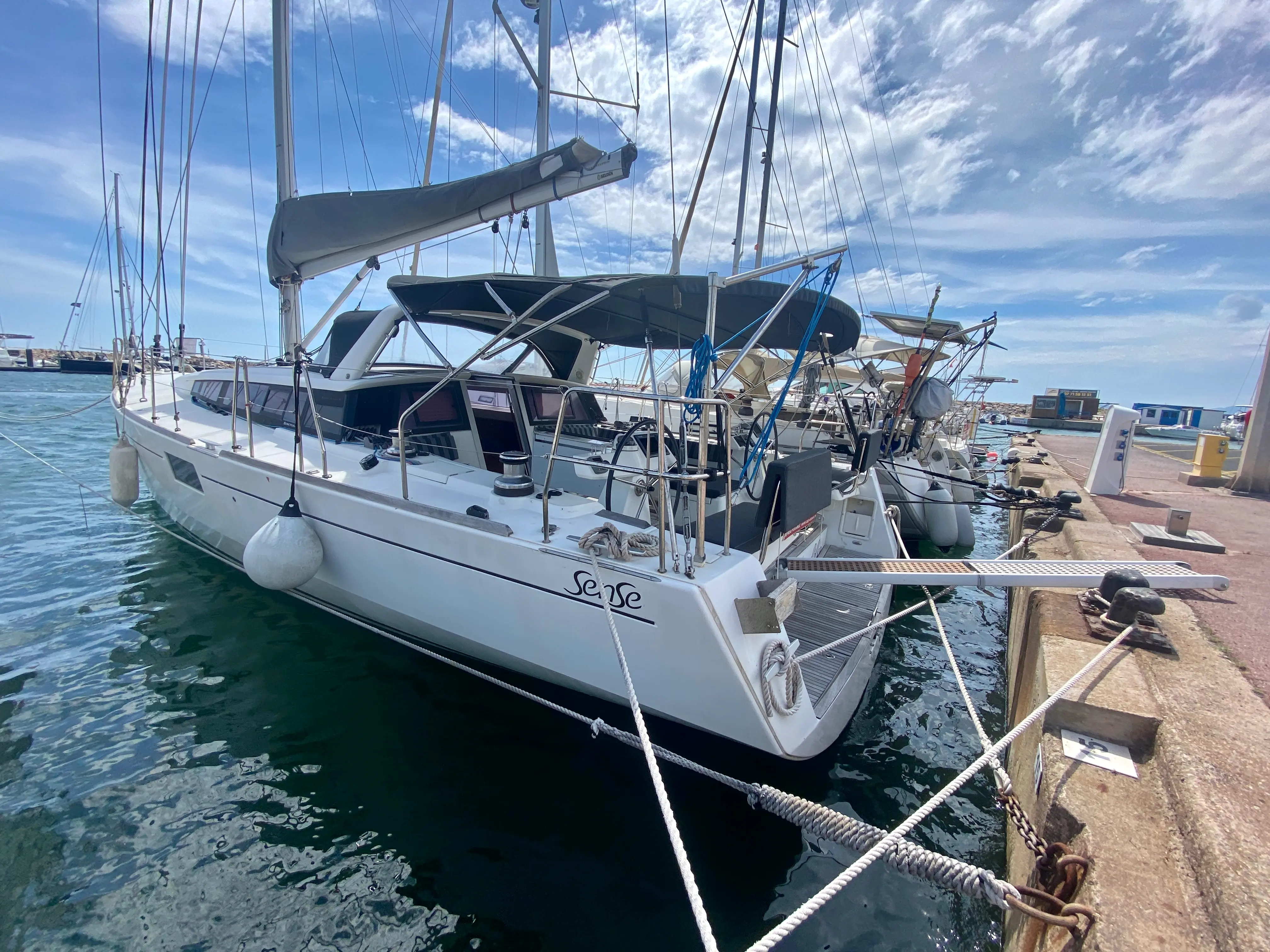 Beneteau Sense 50 — Voilier blanc amarré au port, photographié de trois quarts arrière.