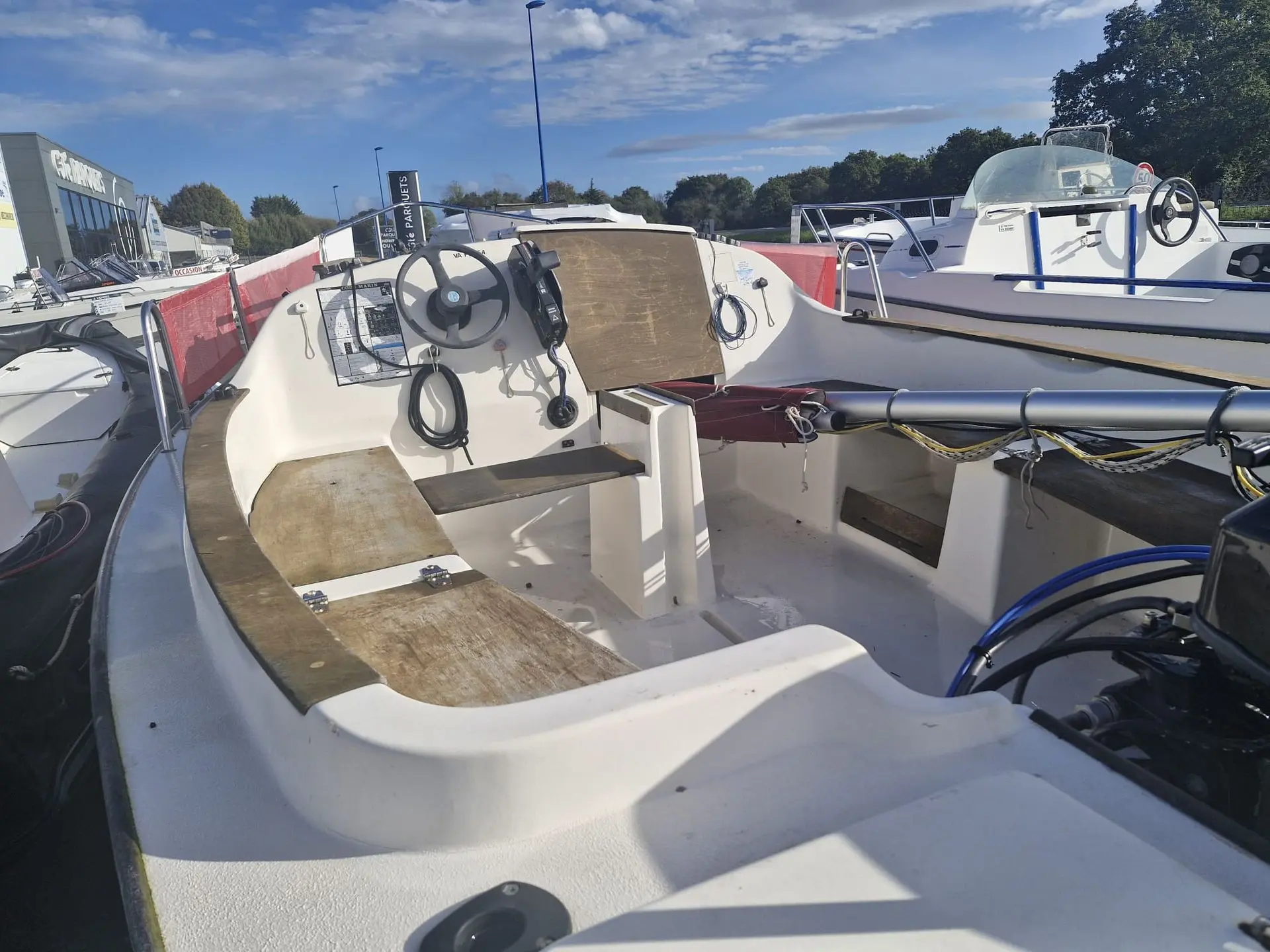 Plasmor Skellig 2 — Vue du cockpit ouvert d’un bateau blanc exposé à terre, avec console et volant.