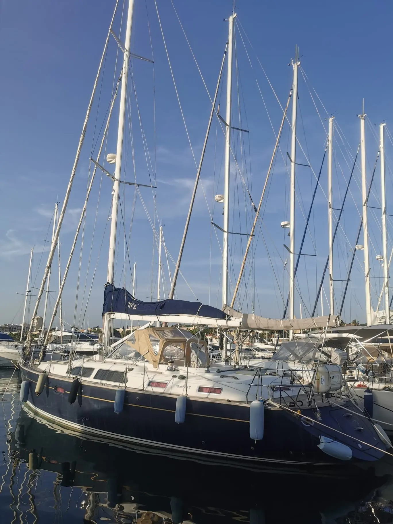 Moody 47 — Voilier amarré dans une marina, vu de profil parmi d'autres bateaux.