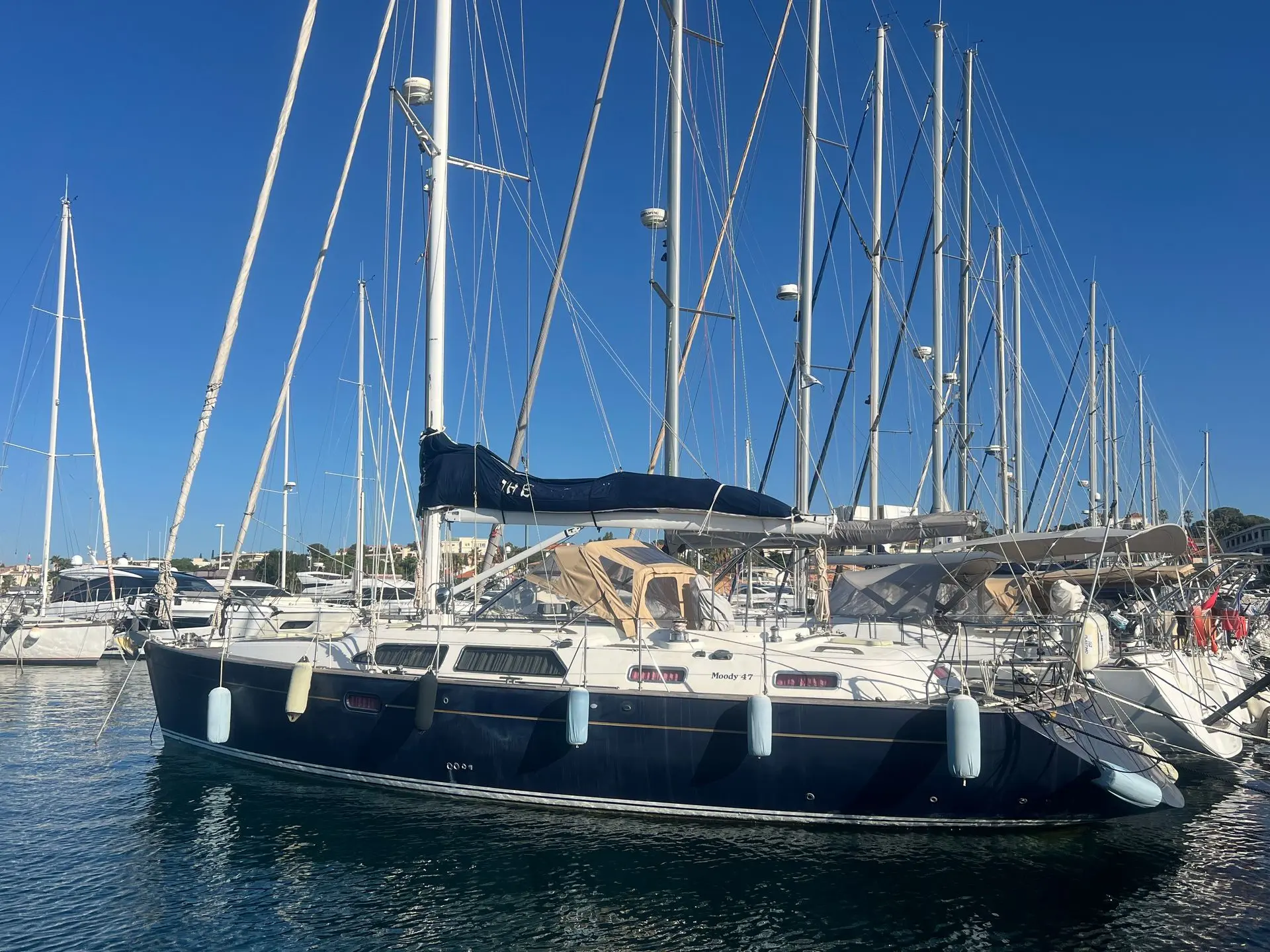 Moody 47 — Voilier bleu et blanc amarré dans une marina, vu de trois quarts.