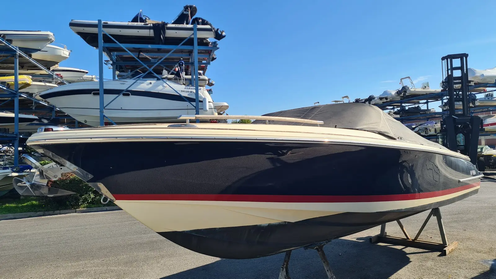 Chris Craft Corsair 25 — Bateau à moteur vu de profil sur ber, dans un parc de stockage nautique.