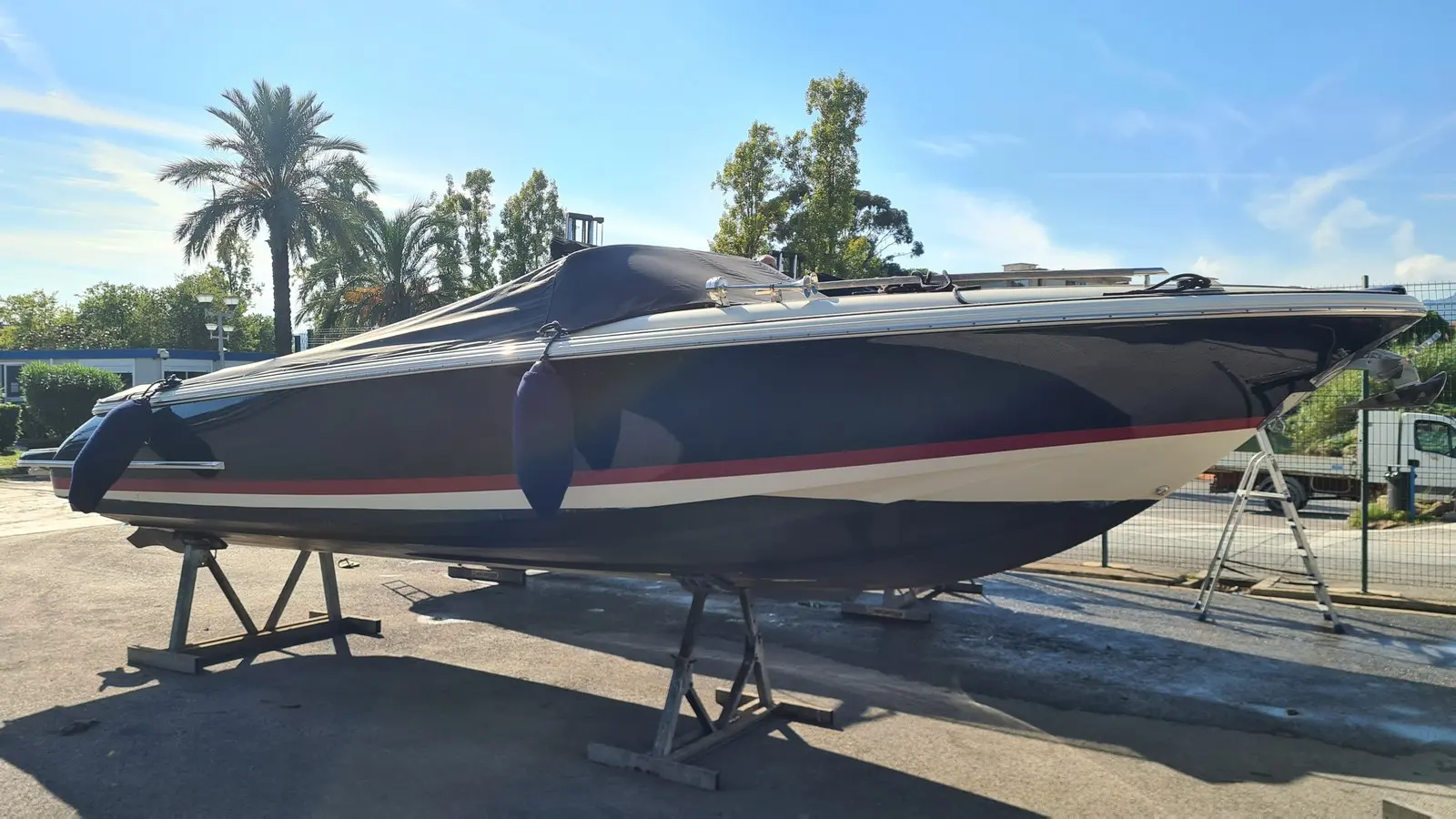 Chris Craft Corsair 25 — Bateau à moteur vu de profil sur bers, avec taud noir et pare-battages.