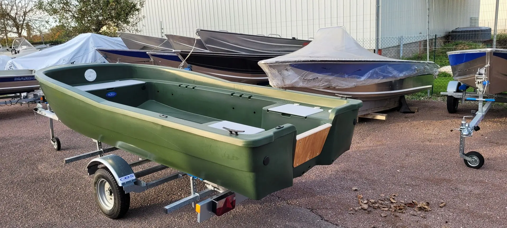Rigiflex Aqua Peche 400 — Barque verte présentée sur une remorque dans une cour extérieure.