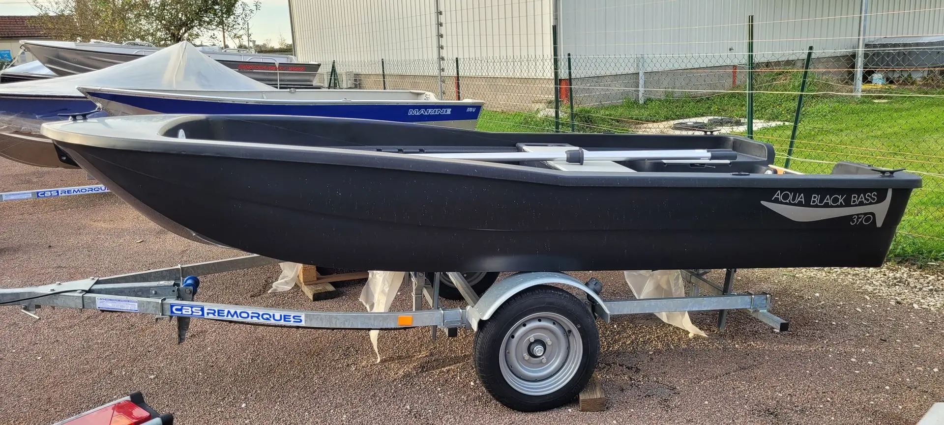 Rigiflex Aqua Peche 400 — Bateau à fond plat noir présenté sur une remorque, vu de profil.