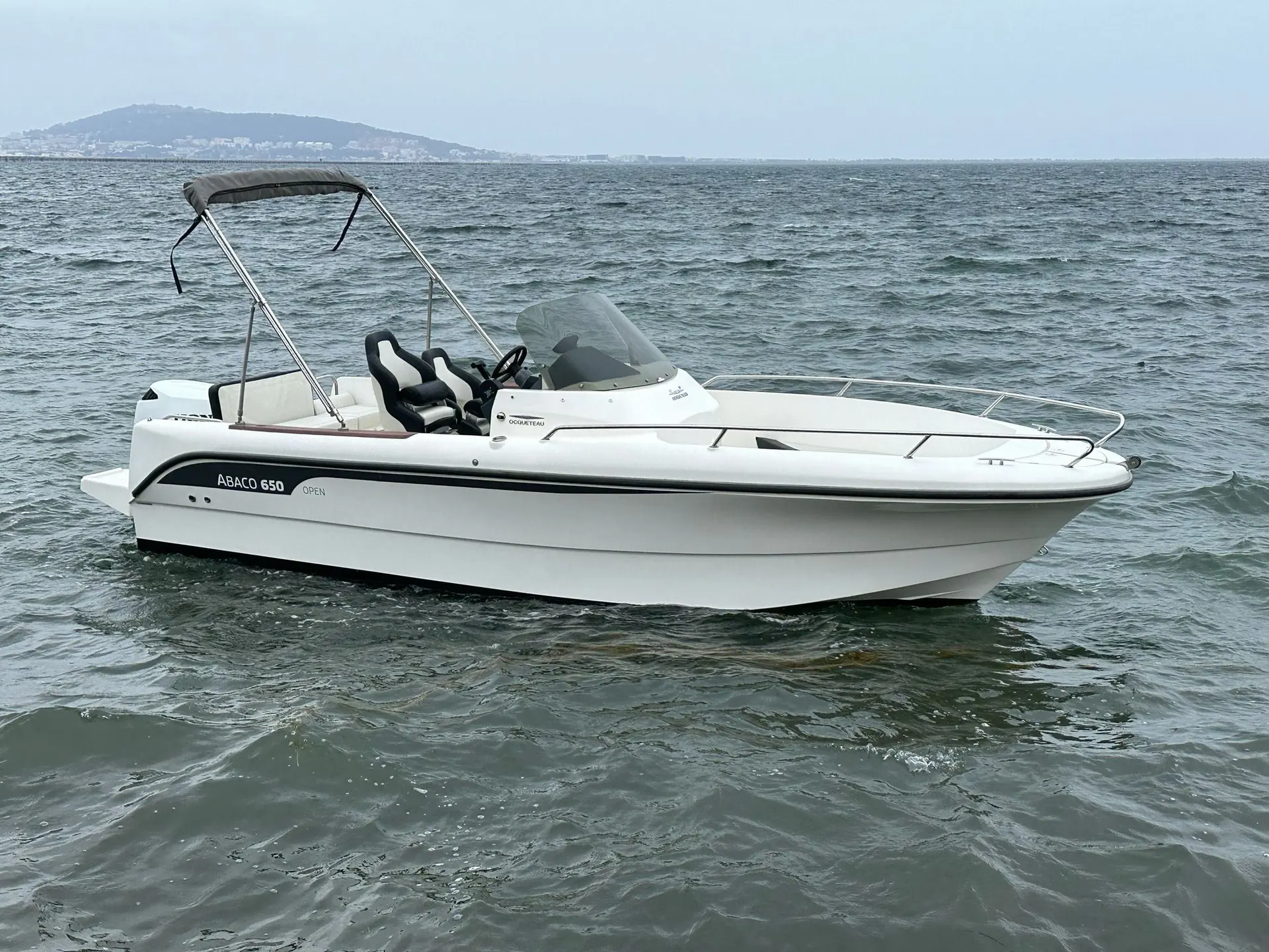 Ocqueteau Abaco 650 Open — Bateau à moteur blanc photographié de profil sur une mer agitée.