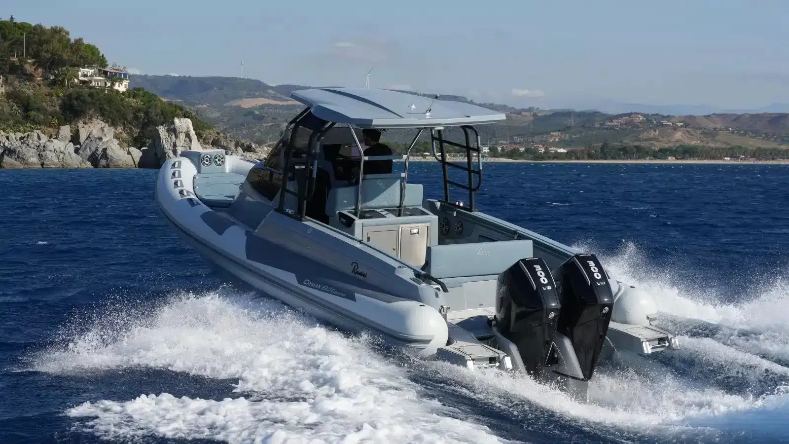 Ranieri Cayman — Bateau pneumatique gris à double moteur hors-bord naviguant près d'une côte.