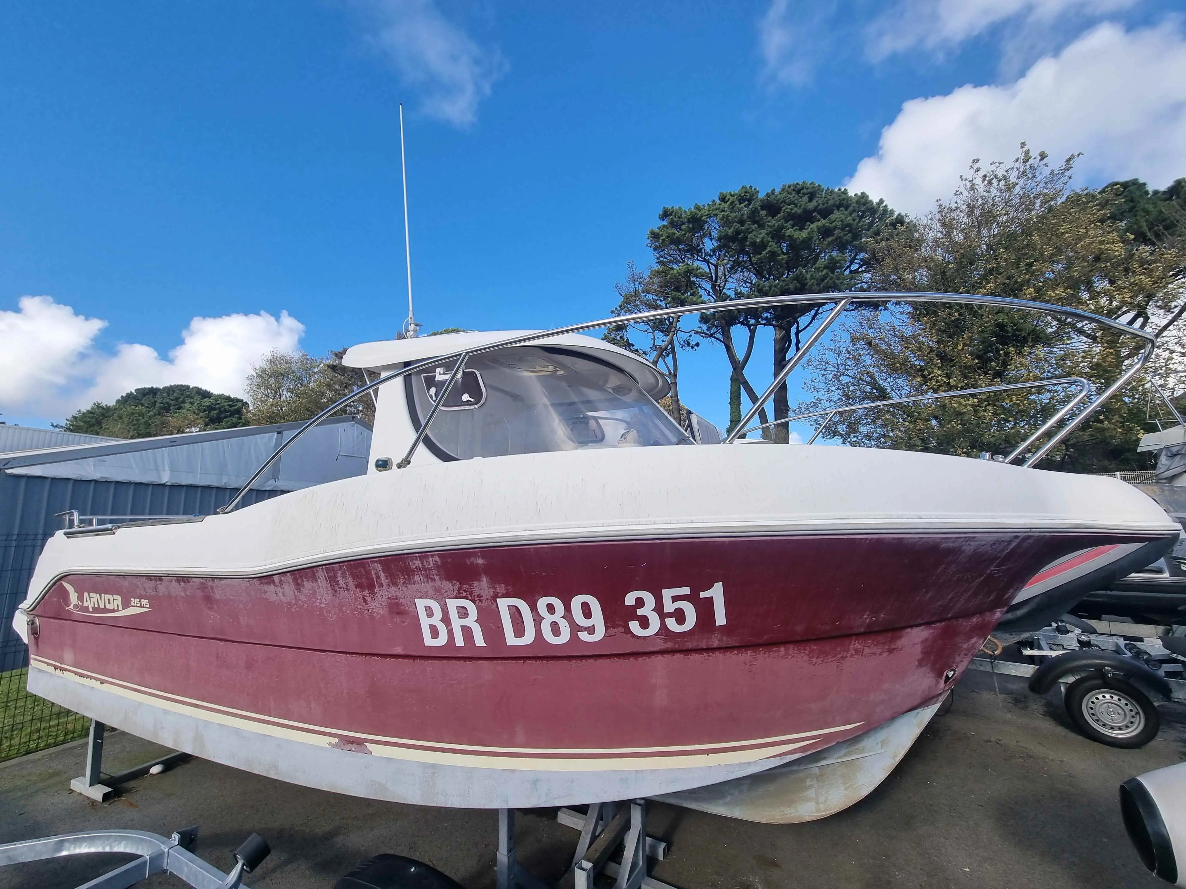 Arvor 215 AS — Bateau à moteur rouge et blanc présenté sur remorque, vu de profil au port.