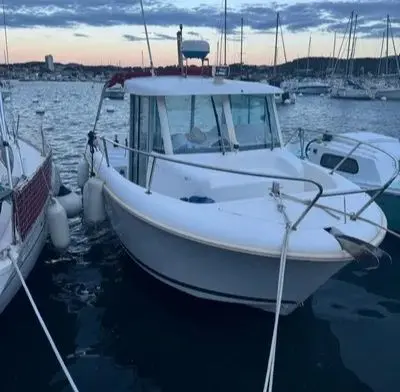 Jeanneau Merry Fisher 655 — Bateau à moteur blanc amarré dans un port, photographié de trois quarts avant.