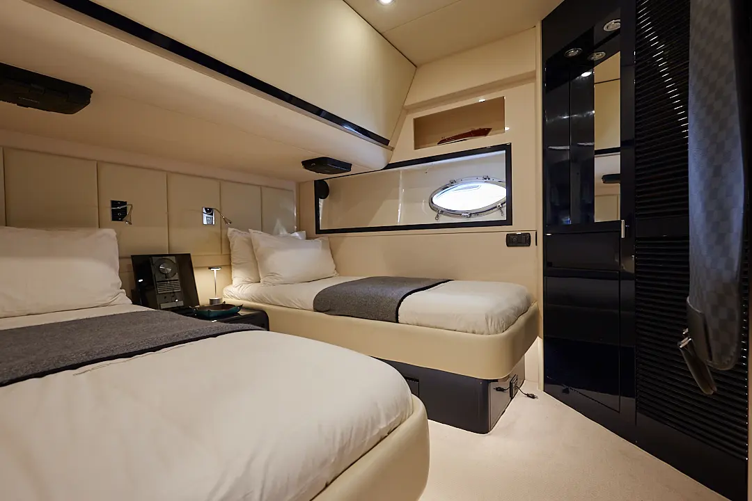 Riva Aquarius 54 — Cabine intérieure avec deux couchettes, rangements et hublot.