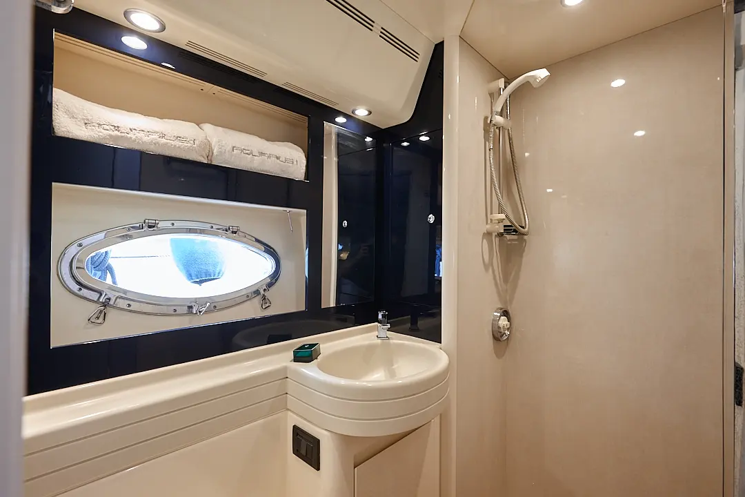 Riva Aquarius 54 — Salle d’eau avec douche, lavabo, miroir et hublot à bord d’un bateau.