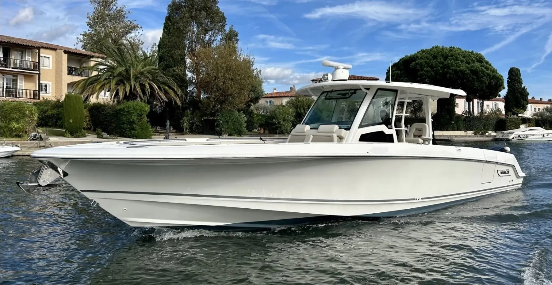 Boston Whaler 380 Outrage — Bateau blanc à cabine naviguant sur un plan d’eau, vu de profil.
