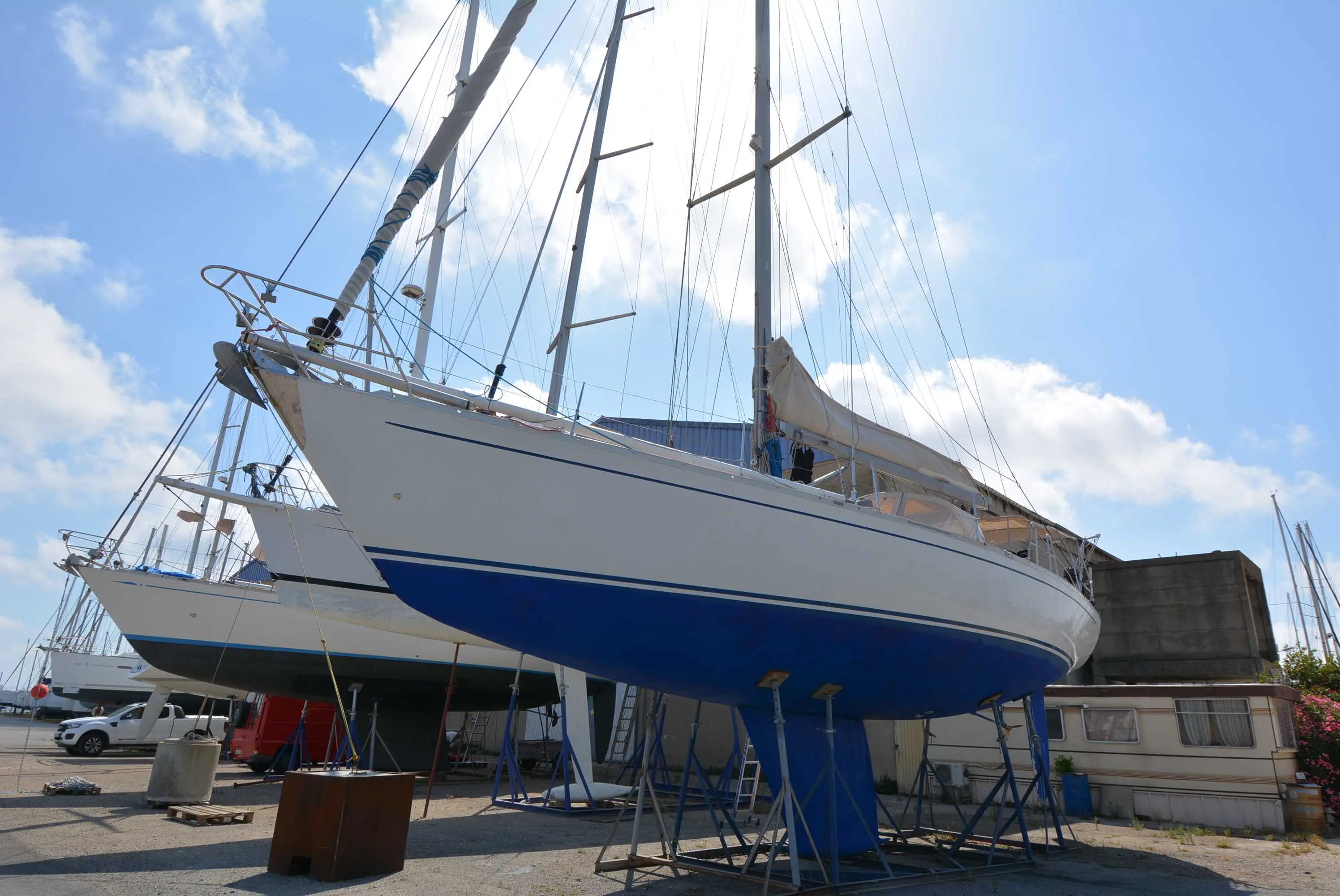 Grand Soleil 52 — Voilier blanc et bleu photographié à terre sur bers, dans un chantier naval.