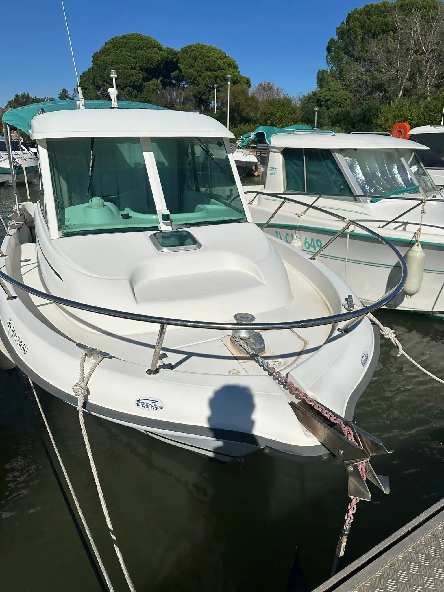 Jeanneau Merry Fisher 635 — Vue avant d’un bateau à cabine amarré au port, entouré d’autres embarcations.
