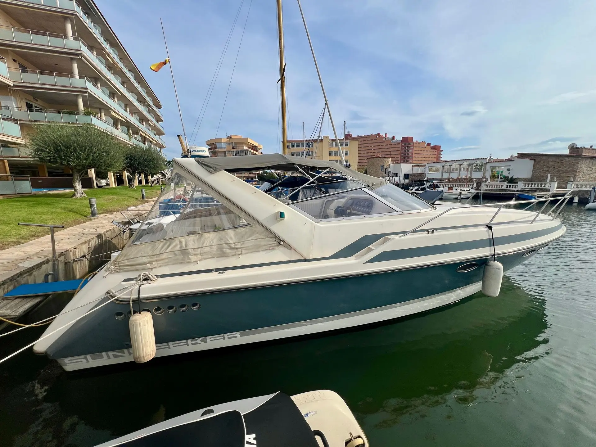 Sunseeker Portofino 34 — Bateau à moteur blanc et bleu amarré dans une marina, vu de trois quarts.