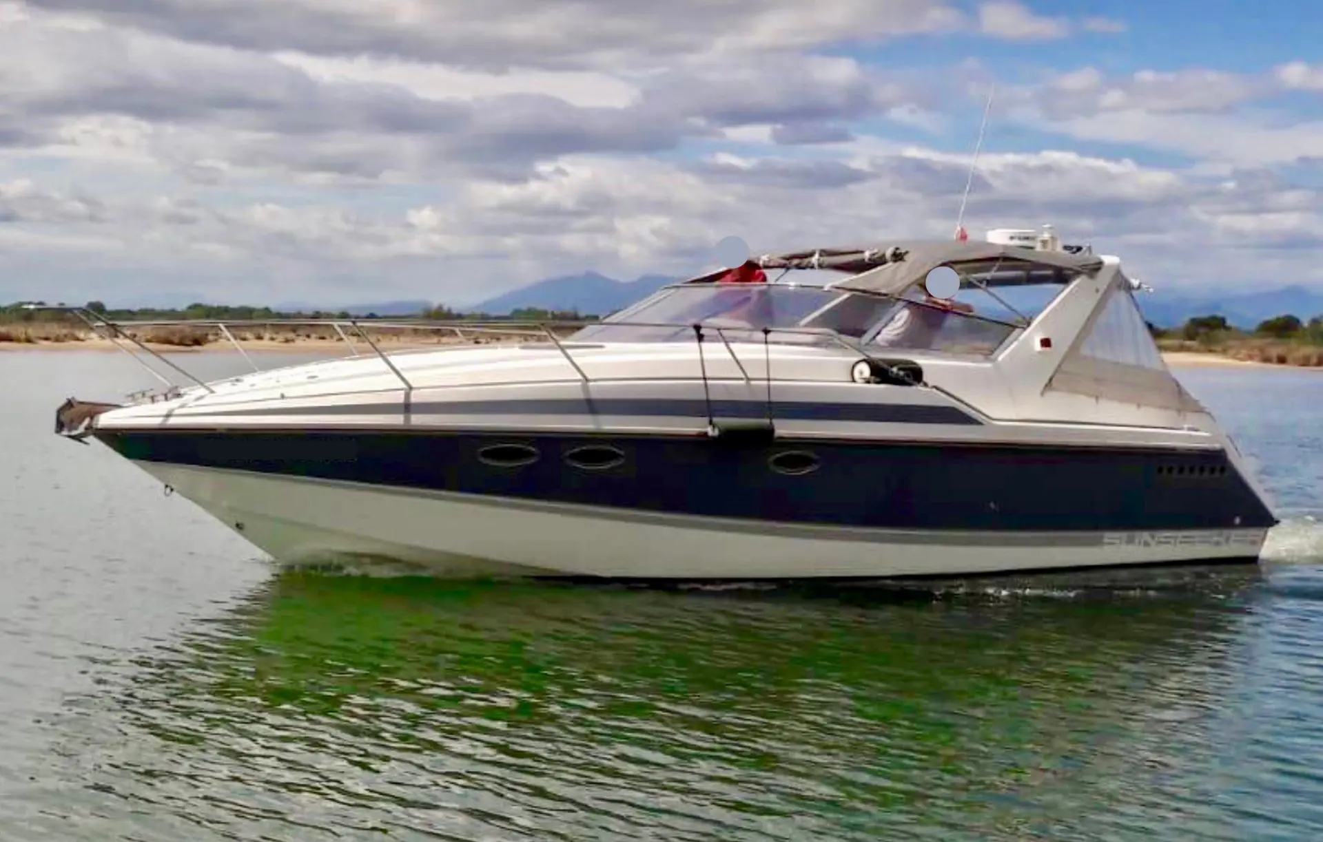 Sunseeker Portofino 34 — Bateau à moteur vu de profil sur l’eau, sous un ciel nuageux.