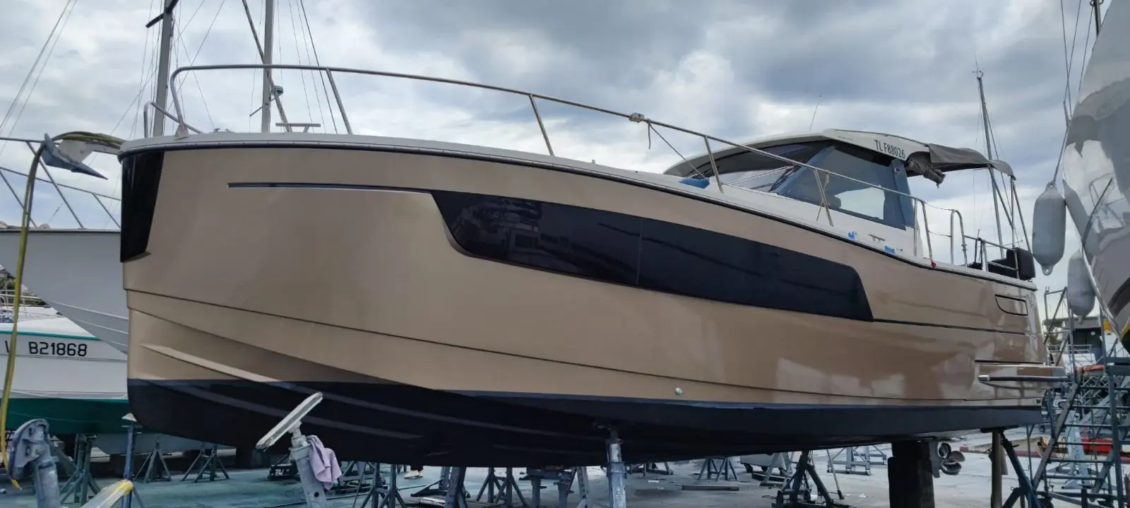 Delphia Escape 1100 Soley — Bateau à moteur beige photographié à terre, vu de profil dans un chantier naval.