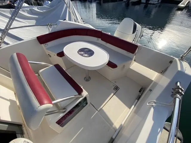 Ocqueteau Abaco 22 — Cockpit arrière avec banquettes, table et moteur hors-bord à quai.