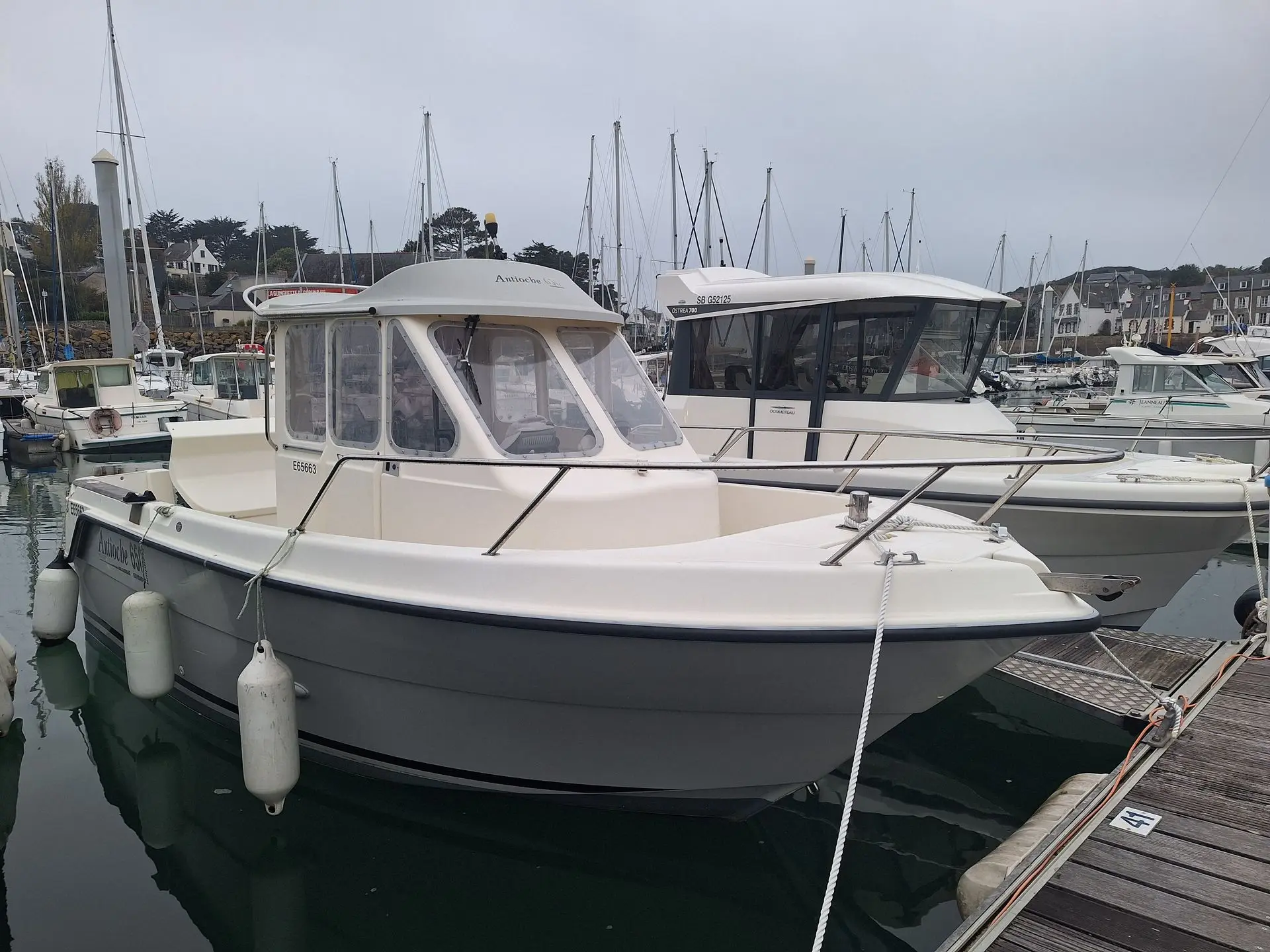 Guymarine Antioche 650 — Bateau à cabine blanche amarré dans un port, vu de trois quarts avant.