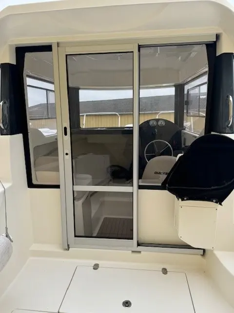 Quicksilver Captur 555 Pilothouse — Vue arrière du cockpit avec cabine vitrée, poste de pilotage et banquette.