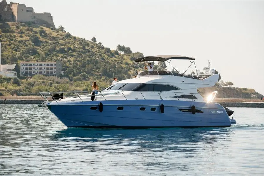 Princess 56 — Bateau à moteur blanc et bleu vu de profil dans un port, avec deux personnes à bord.