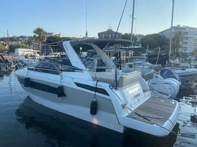 Jeanneau Leader 30 — Bateau à moteur blanc vu de trois quarts arrière dans un port de plaisance.
