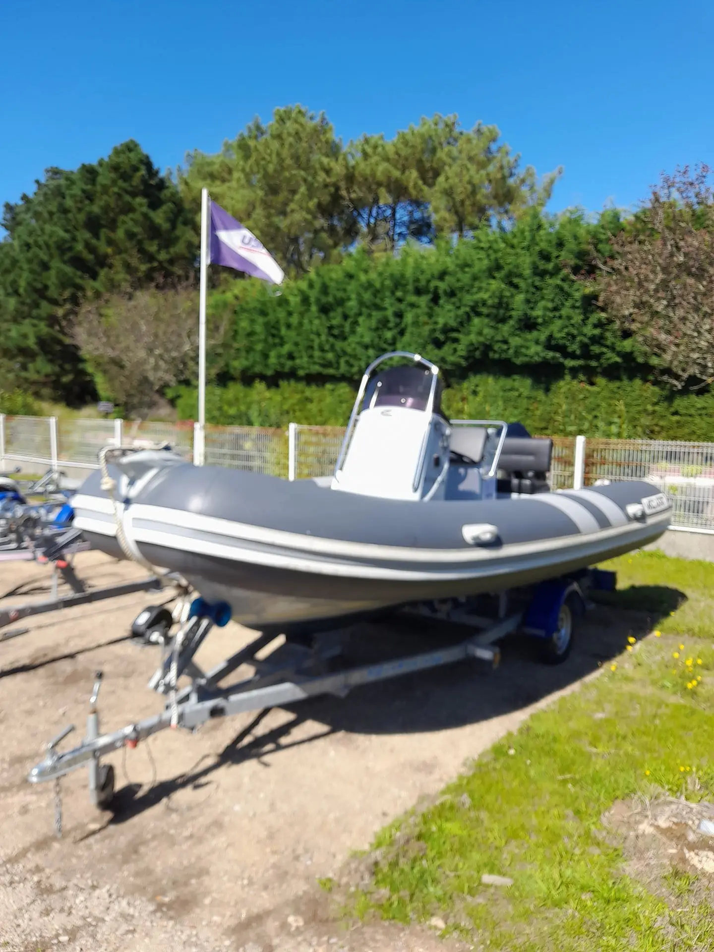 Valiant V 500 Sport — Bateau pneumatique gris exposé sur une remorque devant une clôture.