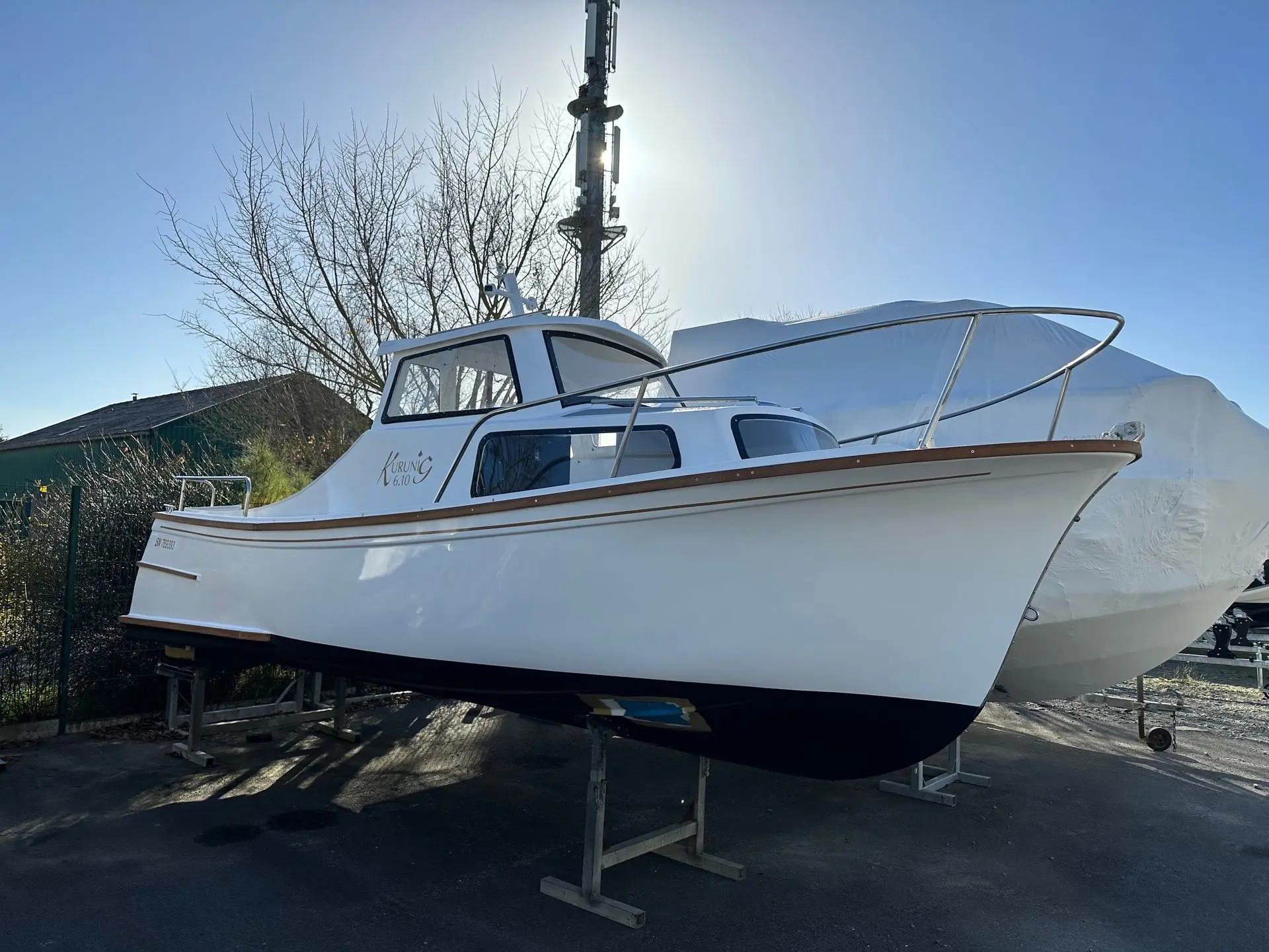 Kurunig 610 — Bateau blanc à cabine photographié de trois quarts sur berceau à terre.
