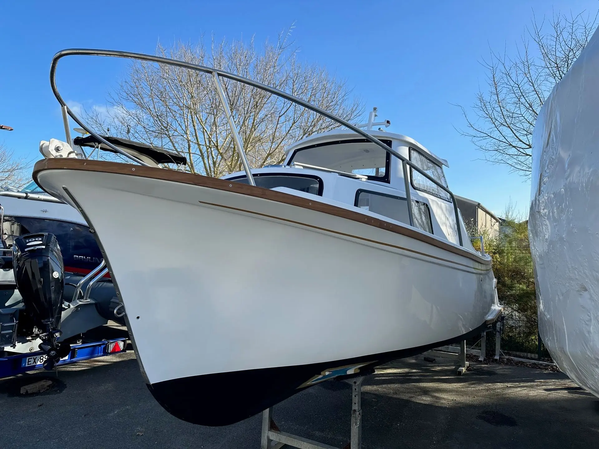 Kurunig 610 — Bateau à moteur blanc à cabine, vu de trois quarts avant sur sa remorque.