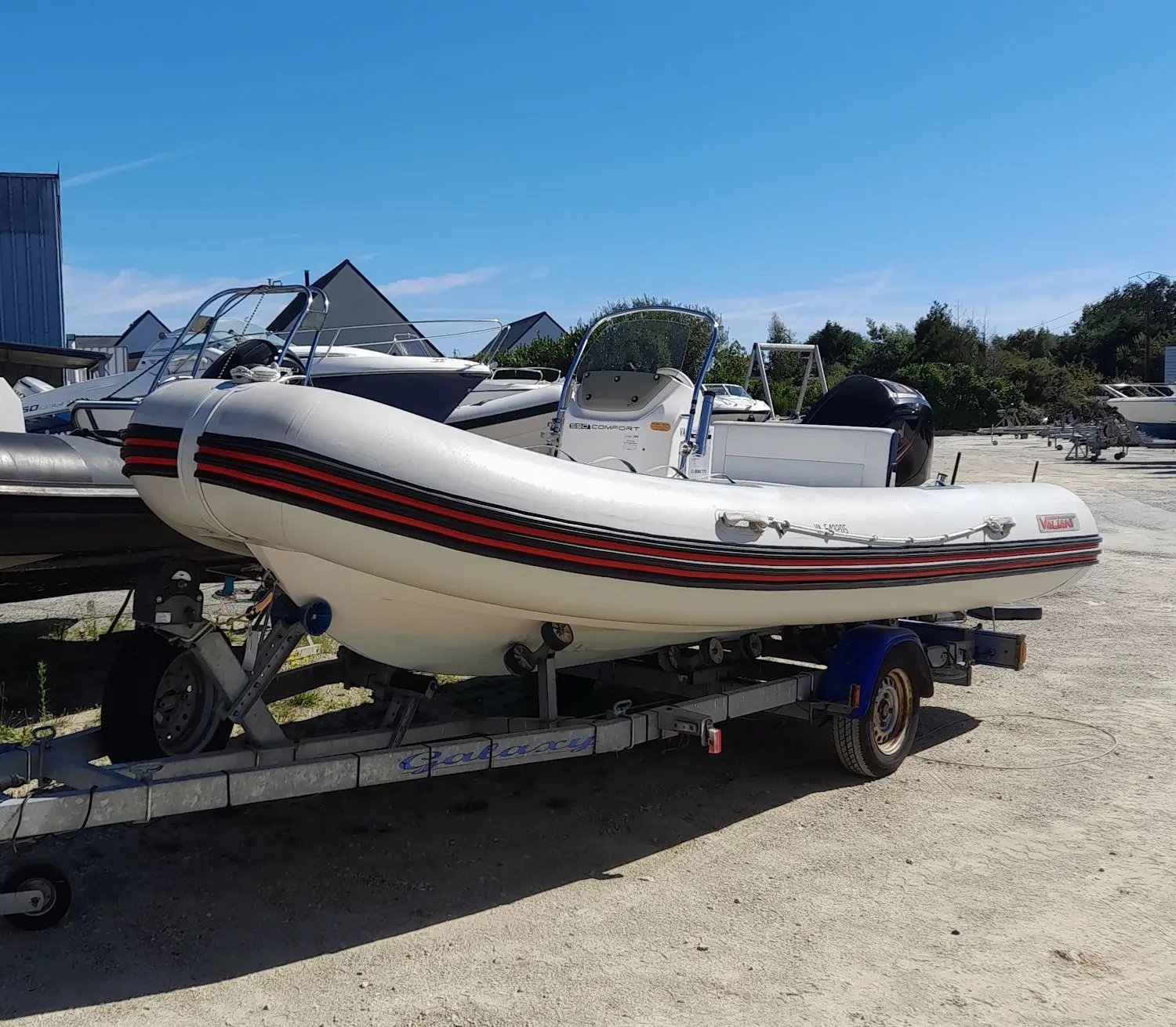 Valiant 550 Comfort — Bateau pneumatique blanc et rouge présenté sur sa remorque dans un parc nautique.