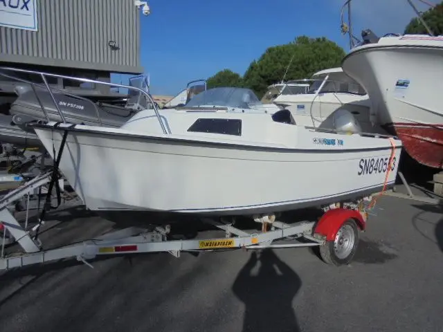 Beneteau Californie 440 — Bateau à moteur blanc sur remorque, photographié sur un parking nautique.