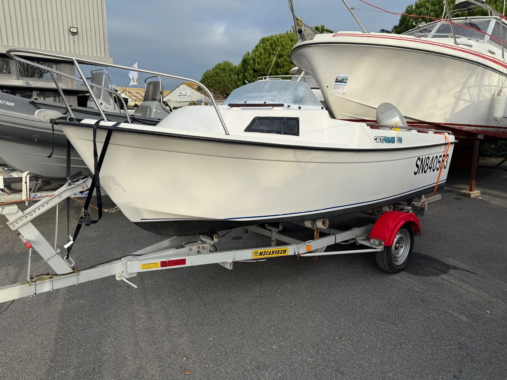 Beneteau Californie 440 — Bateau à moteur blanc sur remorque, photographié de trois quarts à terre.