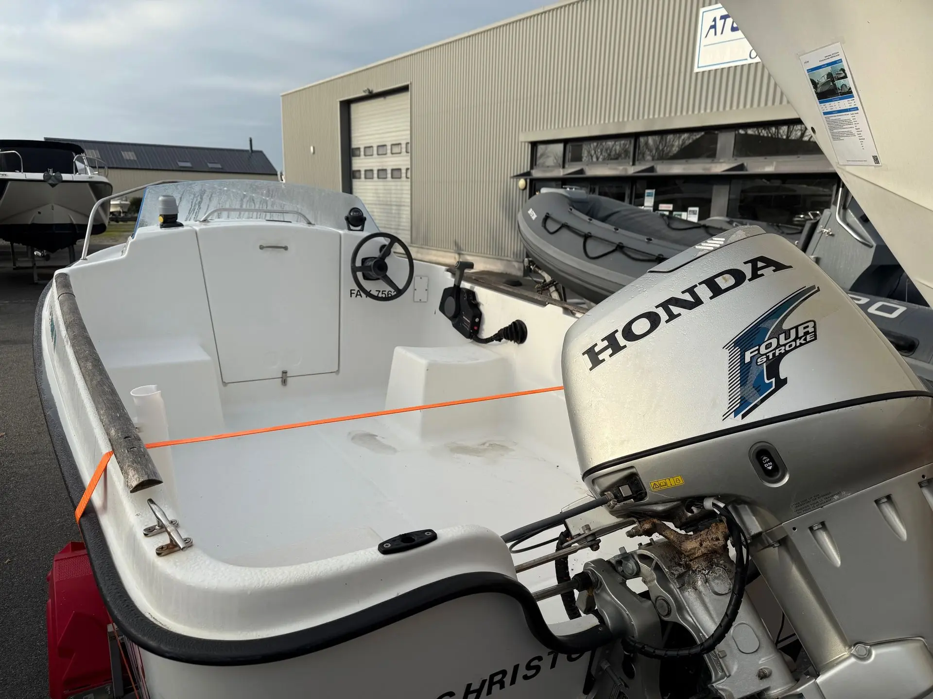 Beneteau Californie 440 — Vue arrière d’un bateau équipé d’un moteur hors-bord Honda devant un bâtiment.