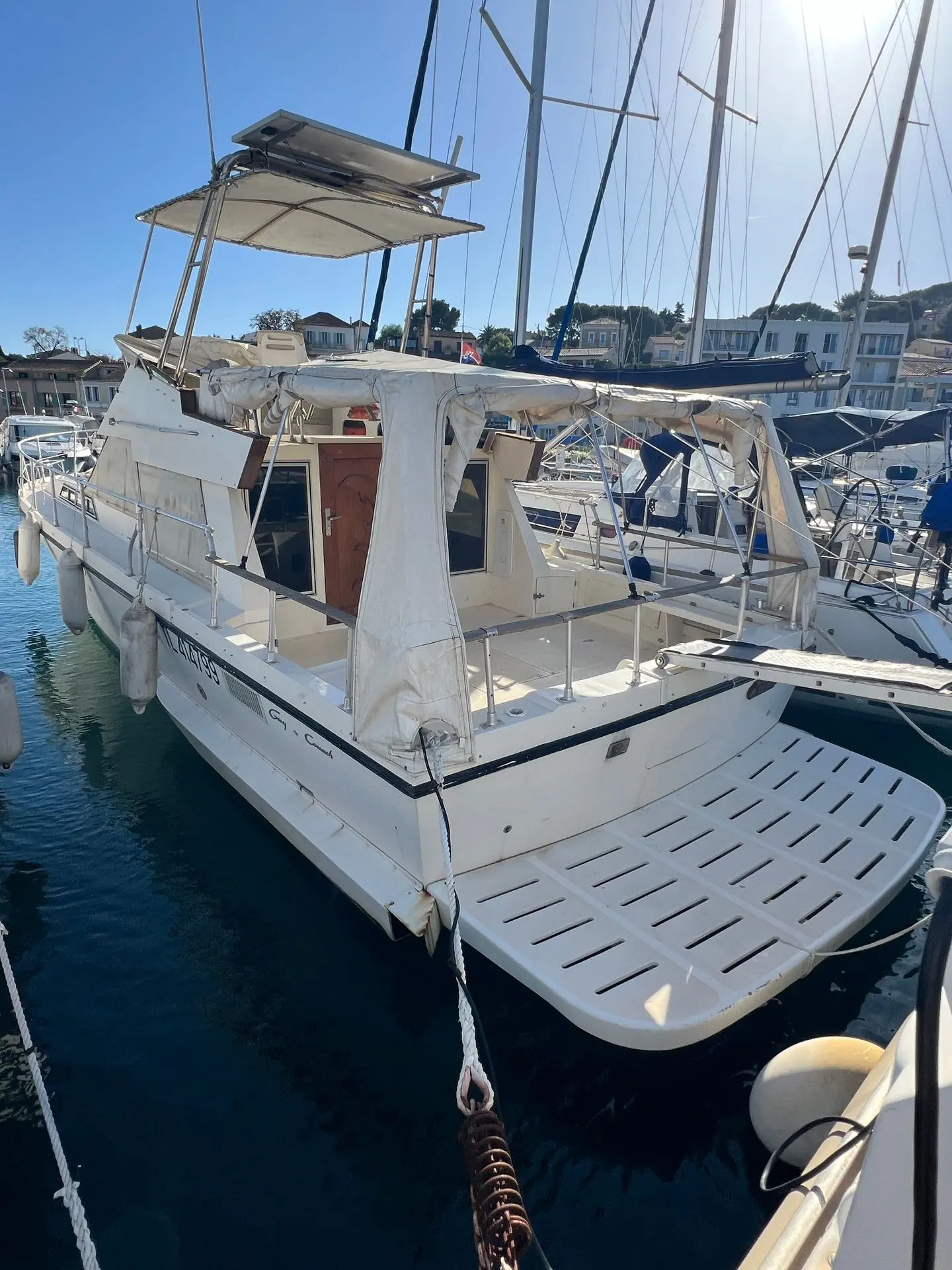 Guy Couach 1200 — Bateau à moteur blanc vu de trois-quarts arrière dans un port.
