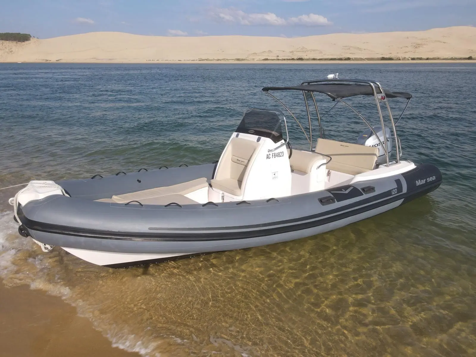 Marsea Comfort 120 — Semi-rigide gris et blanc équipé d’un taud, photographié près d’une plage.