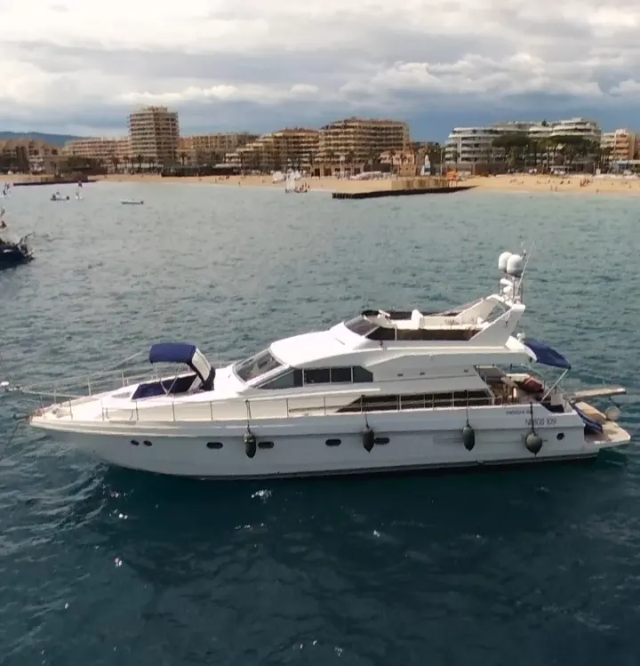 Mochi 56 — Vue latérale d’un yacht à moteur blanc naviguant près d’une plage.