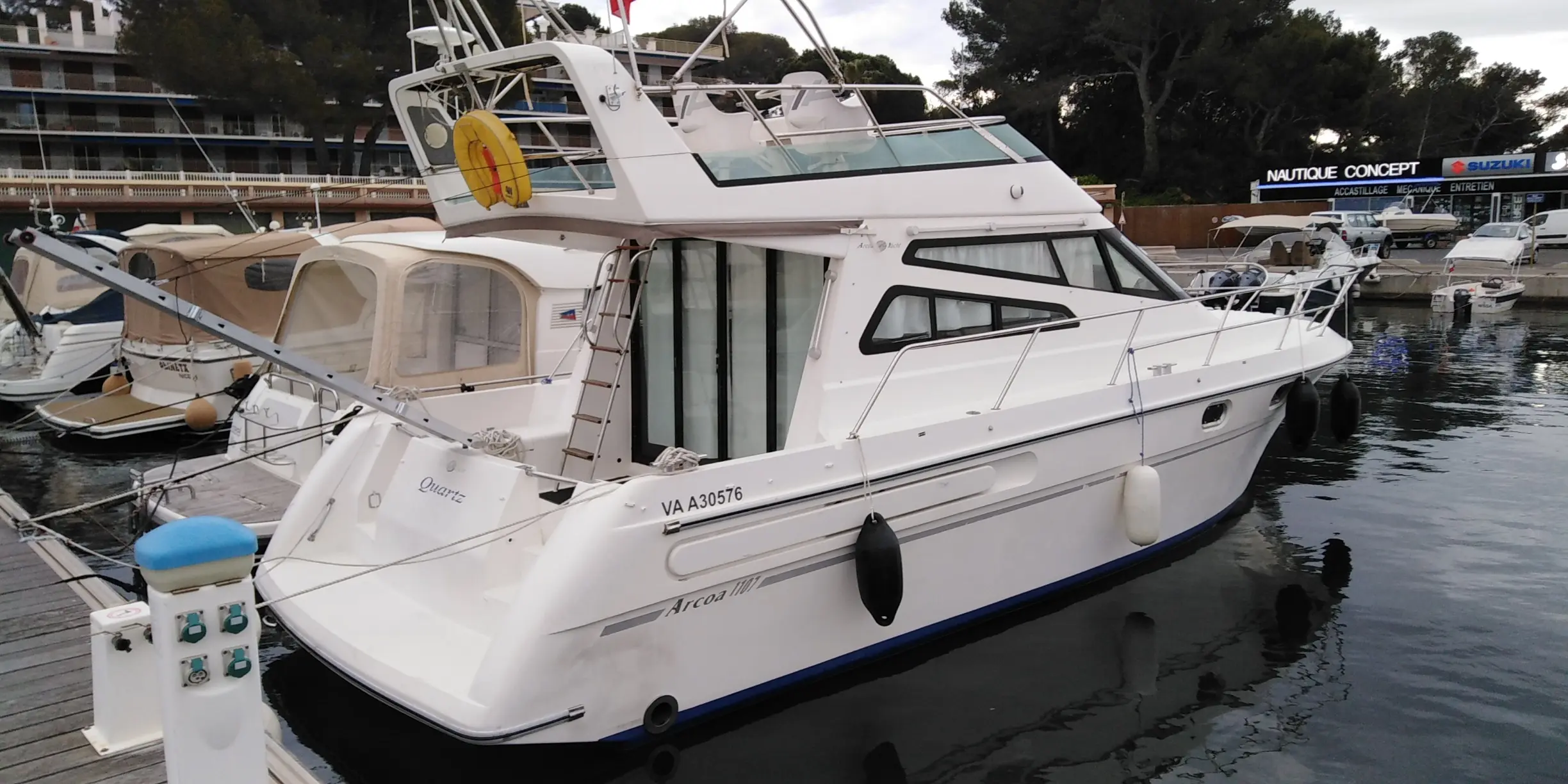Arcoa 1107 — Bateau à moteur blanc amarré dans une marina, vu de trois quarts arrière.