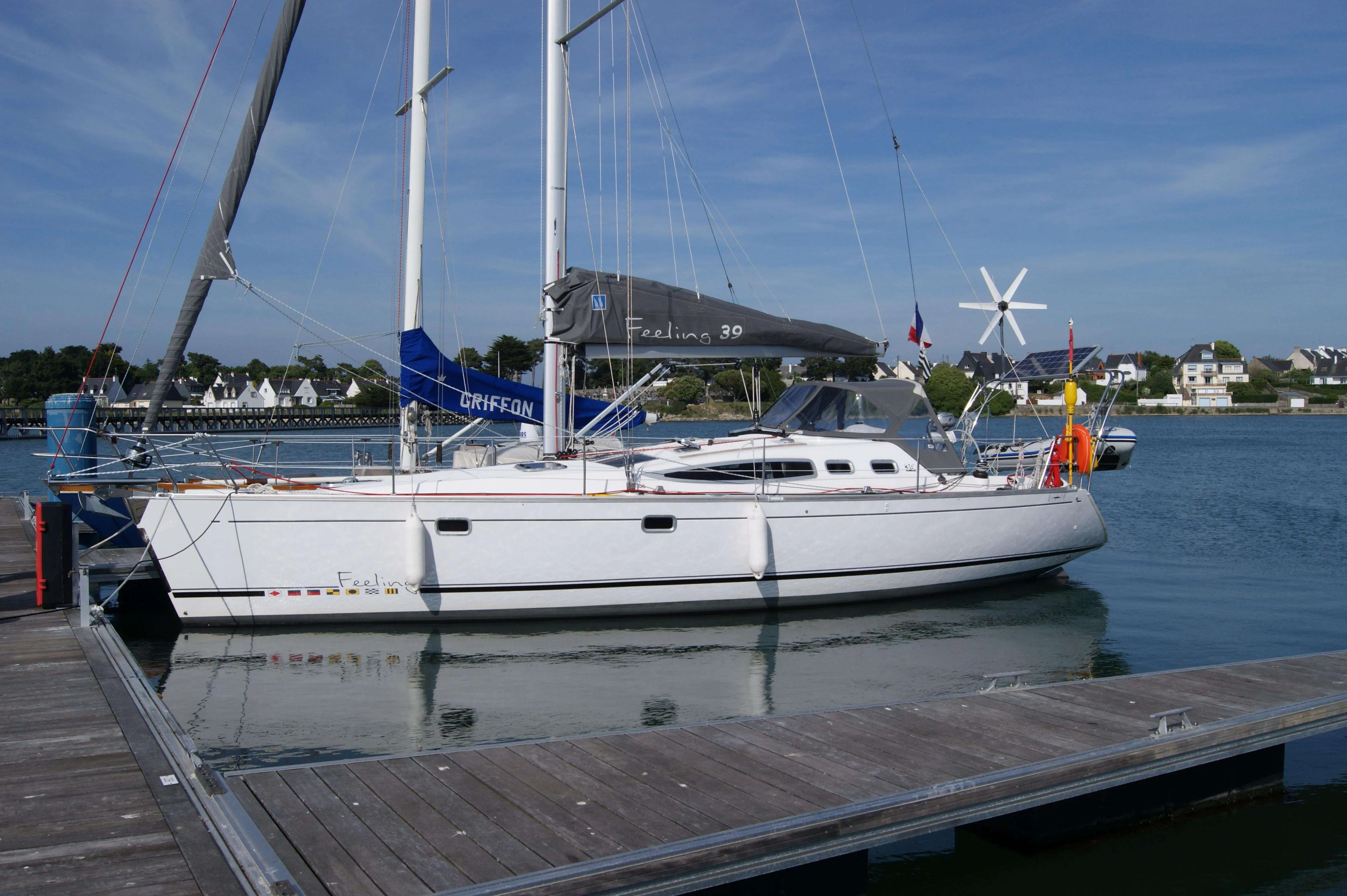 Kirie Feeling 39 — Voilier blanc amarré de profil dans un port, avec voiles et mâts visibles.