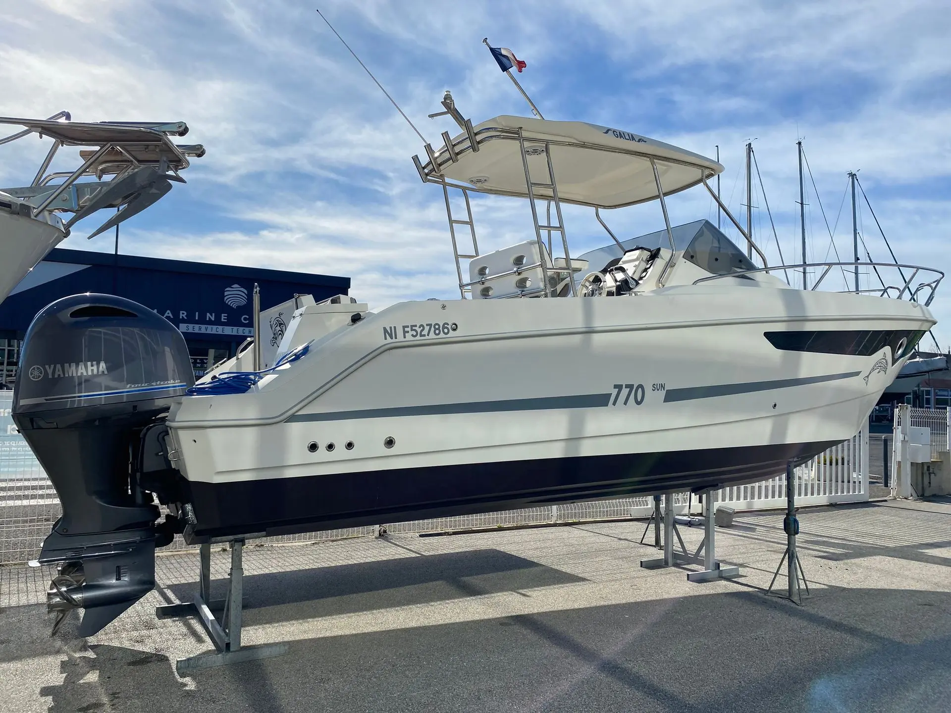 Galia 770 Sun Deck — Bateau à moteur blanc présenté sur bers, vu de trois quarts à l’extérieur.