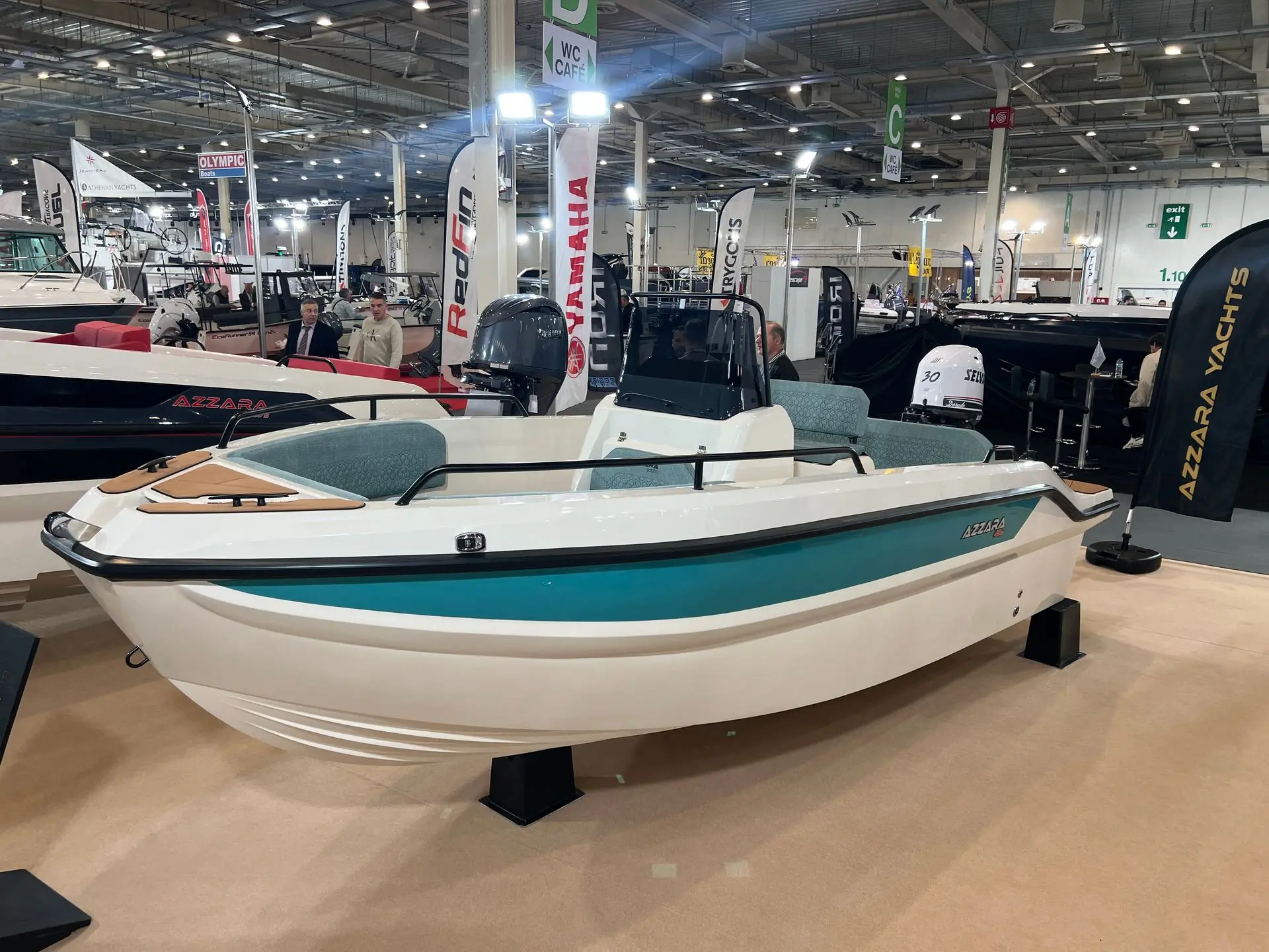 Azzara 49s — Bateau à moteur exposé sur un stand de salon nautique, vu de trois quarts.