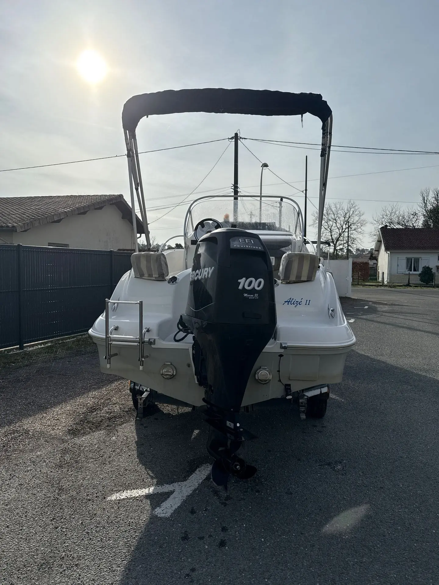 Quicksilver 555 Commander — Vue arrière d’un bateau à moteur hors-bord stationné sur une remorque.