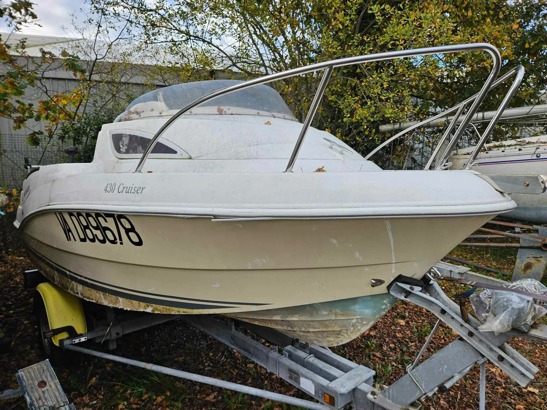 Quicksilver 430 — Bateau à moteur blanc de profil sur remorque, stationné à terre.
