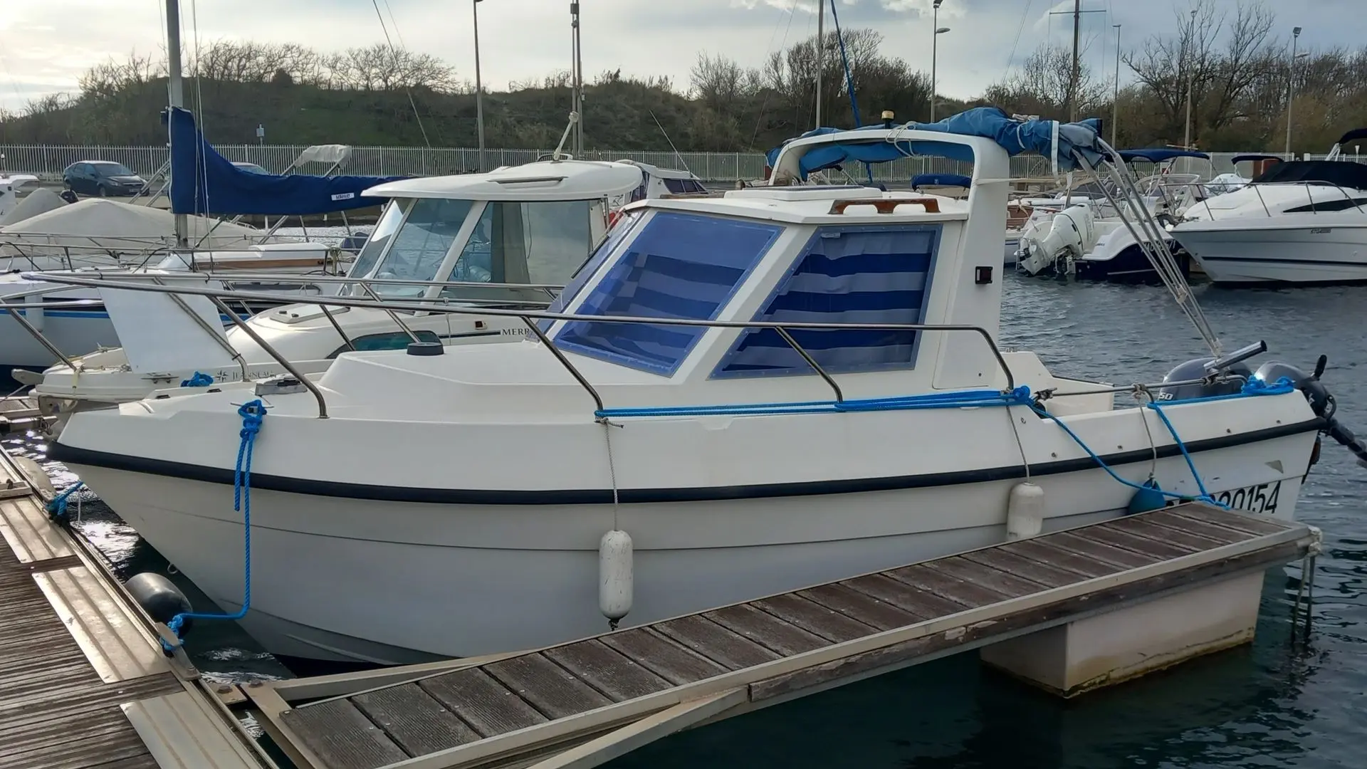 Clear Liner 600 — Bateau à moteur blanc amarré dans un port de plaisance.