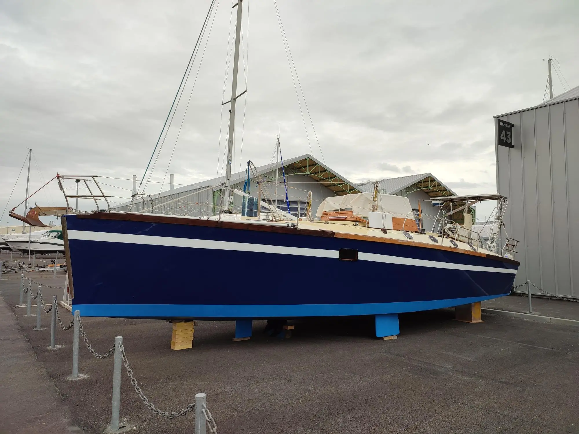 Yorc 40 — Voilier bleu et blanc présenté à terre devant des hangars nautiques.