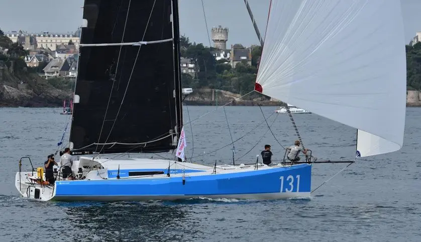 Akilaria RC3 — Voilier bleu et blanc naviguant sous voiles, avec plusieurs personnes à bord.