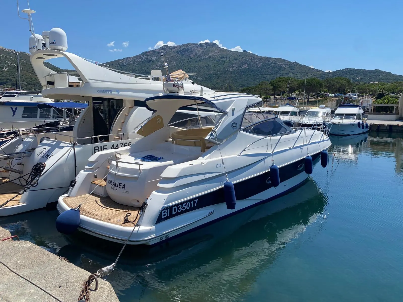 Sessa Marine C42 — Bateau à moteur blanc amarré dans une marina, avec montagne en arrière-plan.