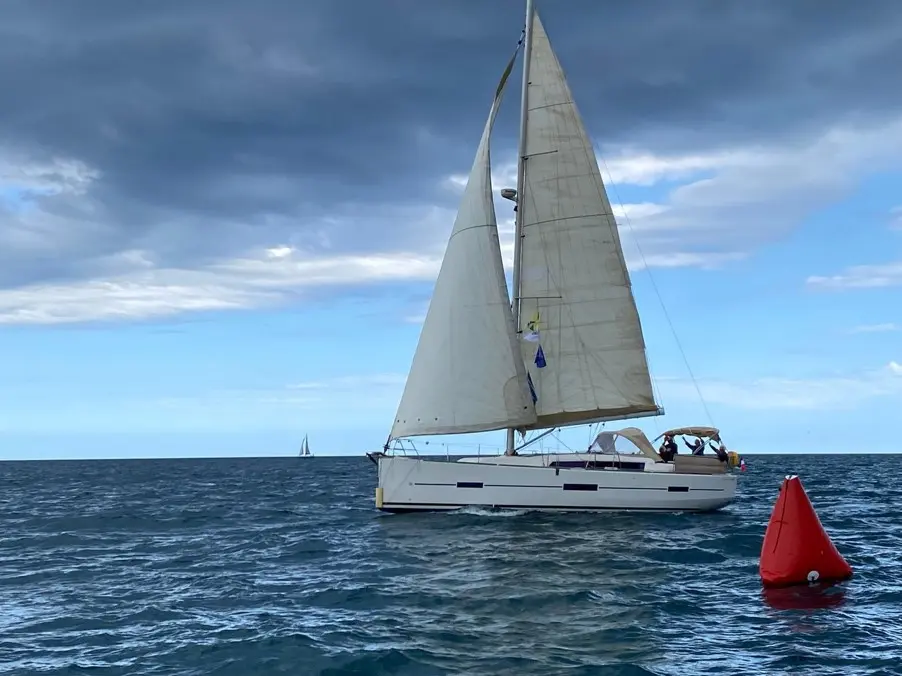 Dufour 410 — Voilier blanc naviguant toutes voiles dehors, avec une bouée rouge au premier plan.