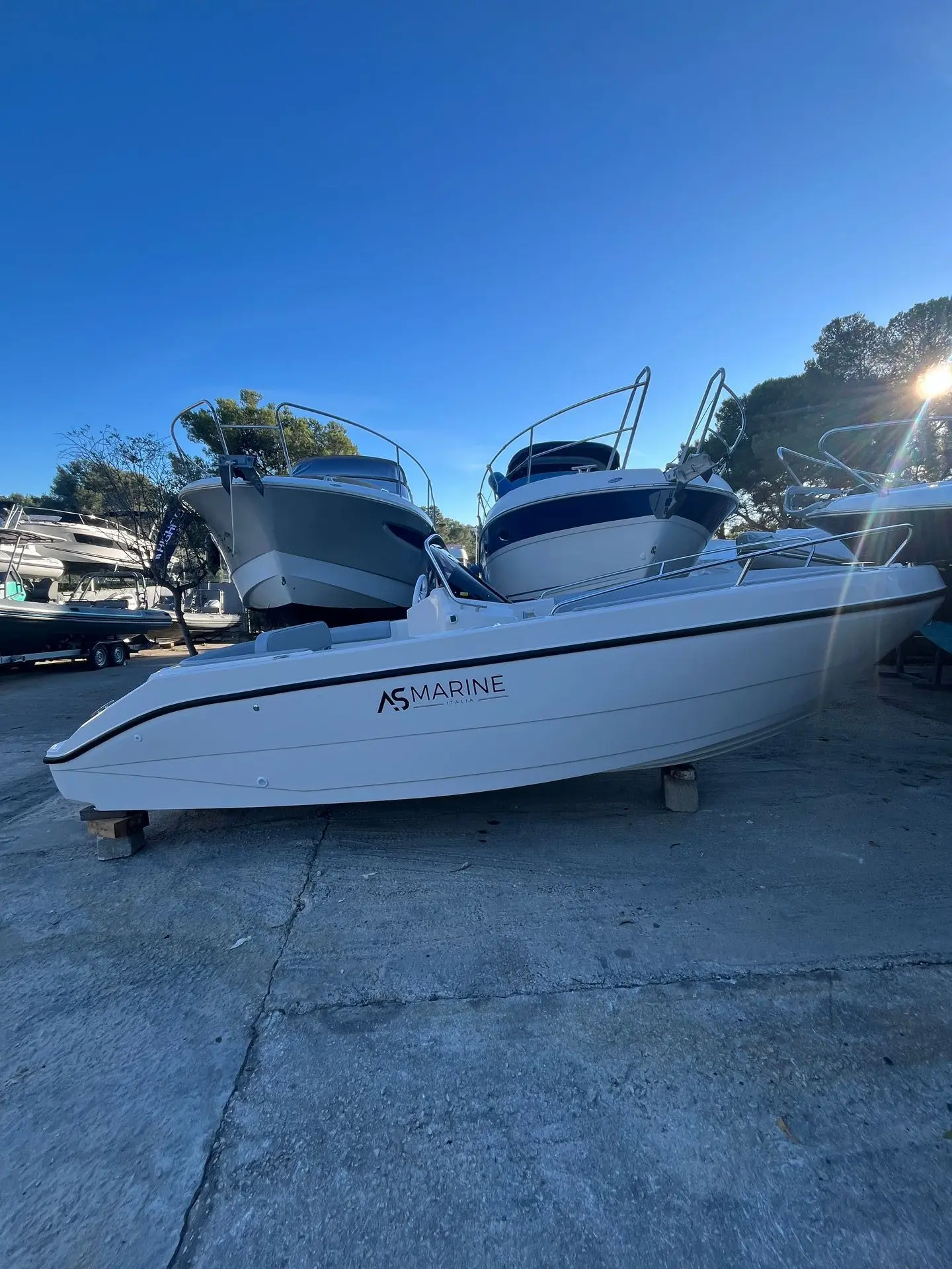 Eolo AS 19GL OPEN — Bateau à moteur blanc photographié à terre, vu de profil dans une zone de stockage.